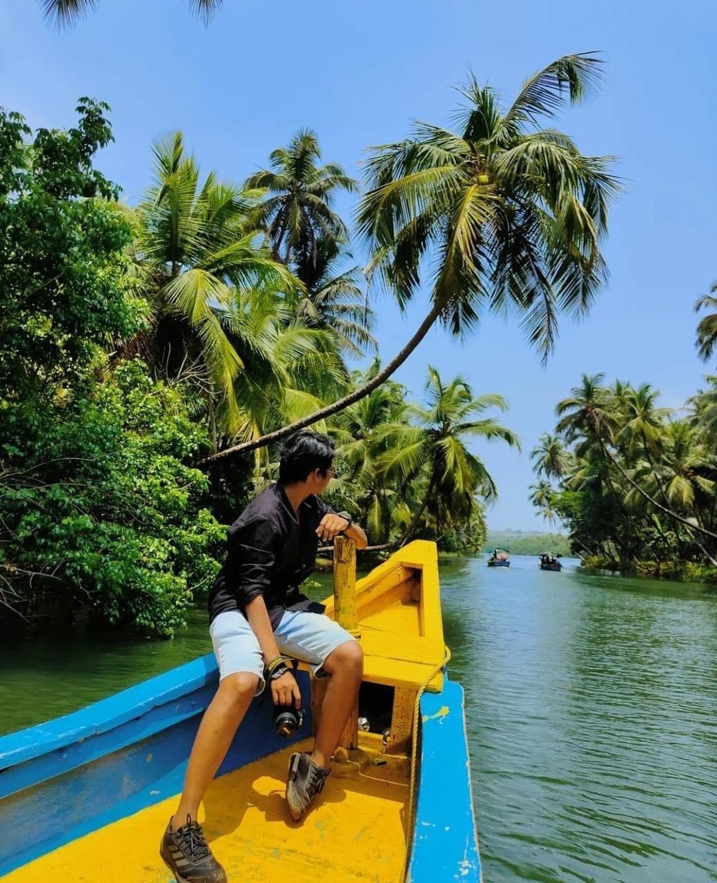 Guest on the bow under leaning coconut palms