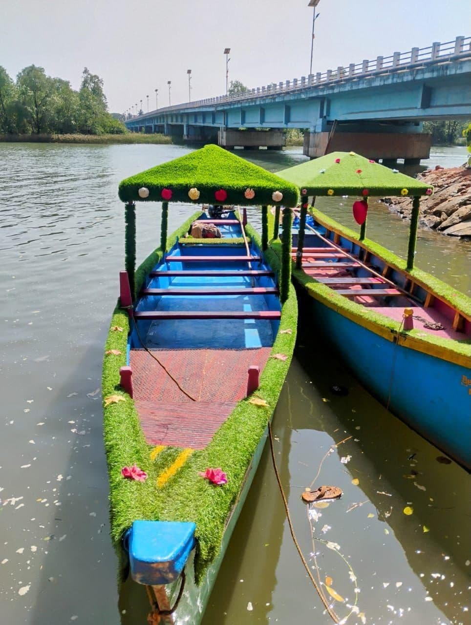 Green-roofed boats lined up under the Honnavar bridge