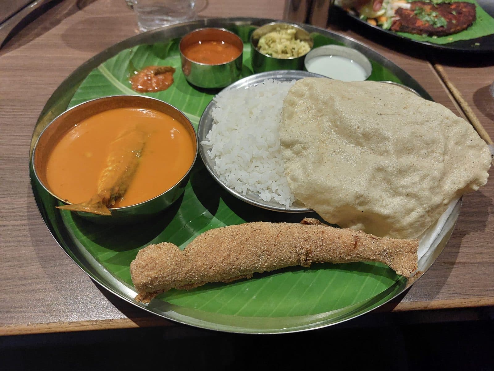 Mangalorean fish meal on a banana leaf with rice, curry and fried fish