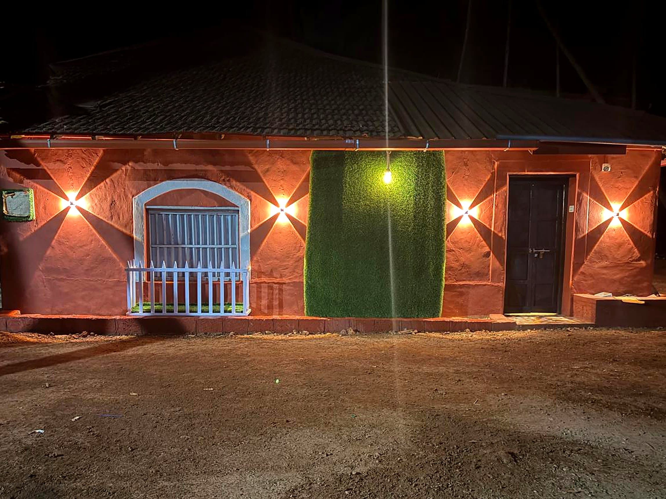 De antique Pauli's Homestay at night, laterite walls lit by warm wall lamps