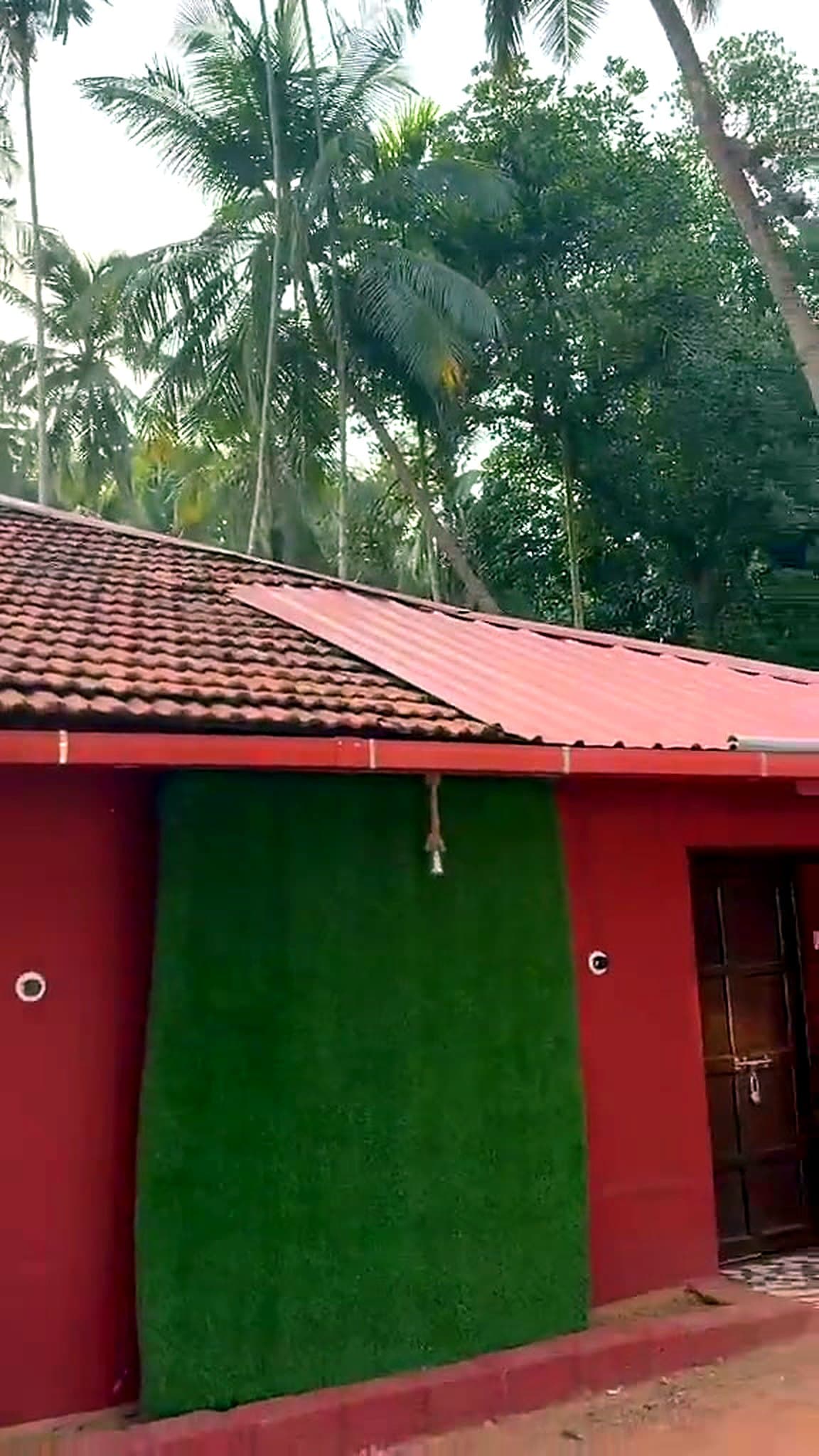 Red laterite front of De antique Pauli's Homestay with tiled roof under coconut palms